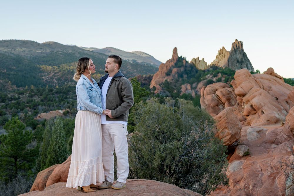 A couple stands together on red rocks with the iconic Garden of the Gods formations behind them.