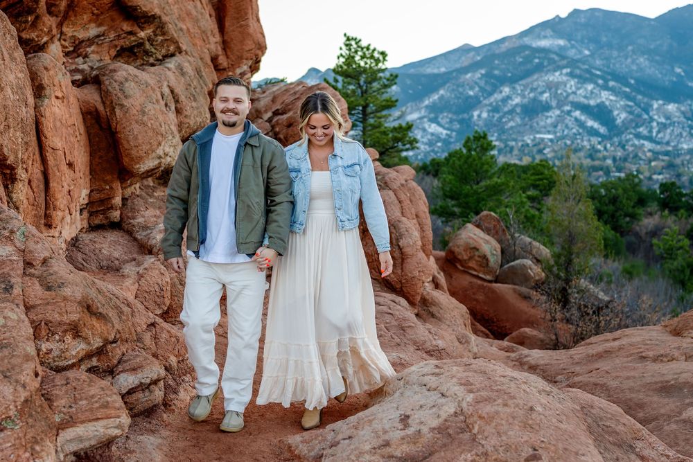 Casual portrait session on red rocks with Pikes Peak mountain range in background.