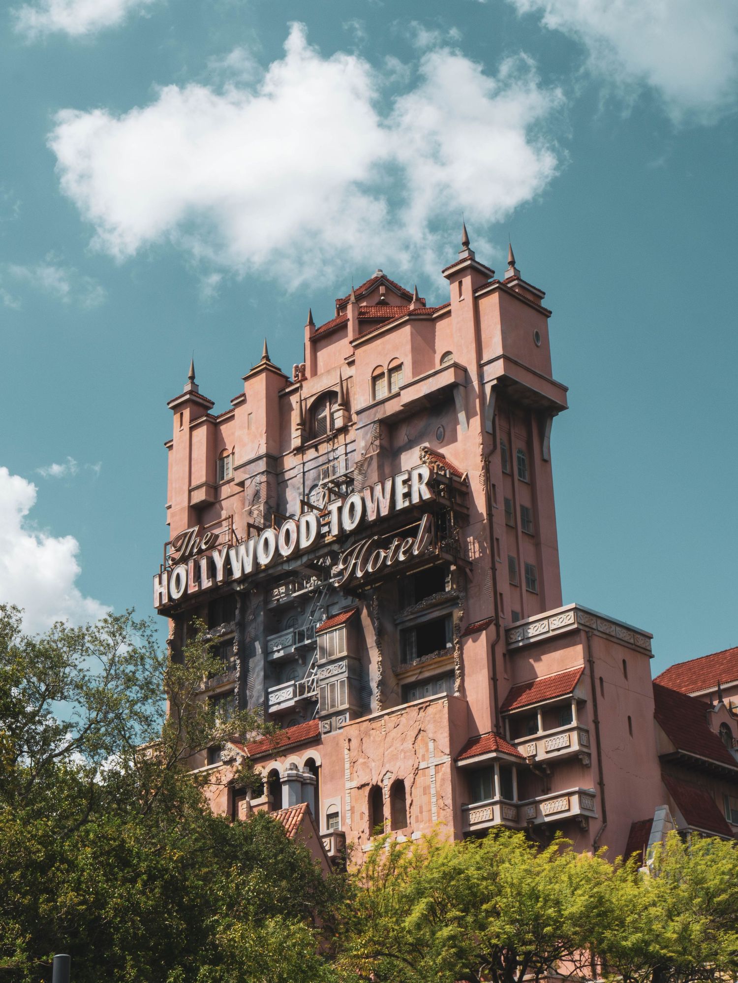The Hollywood Tower Hotel attraction at Disney's Hollywood Studios shown from multiple angles against a blue sky.