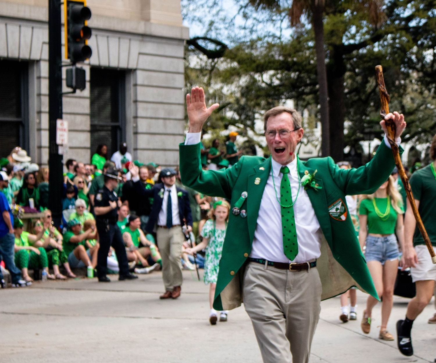 Parade participant in green jacket celebrates during St. Patrick's Day festivities.
