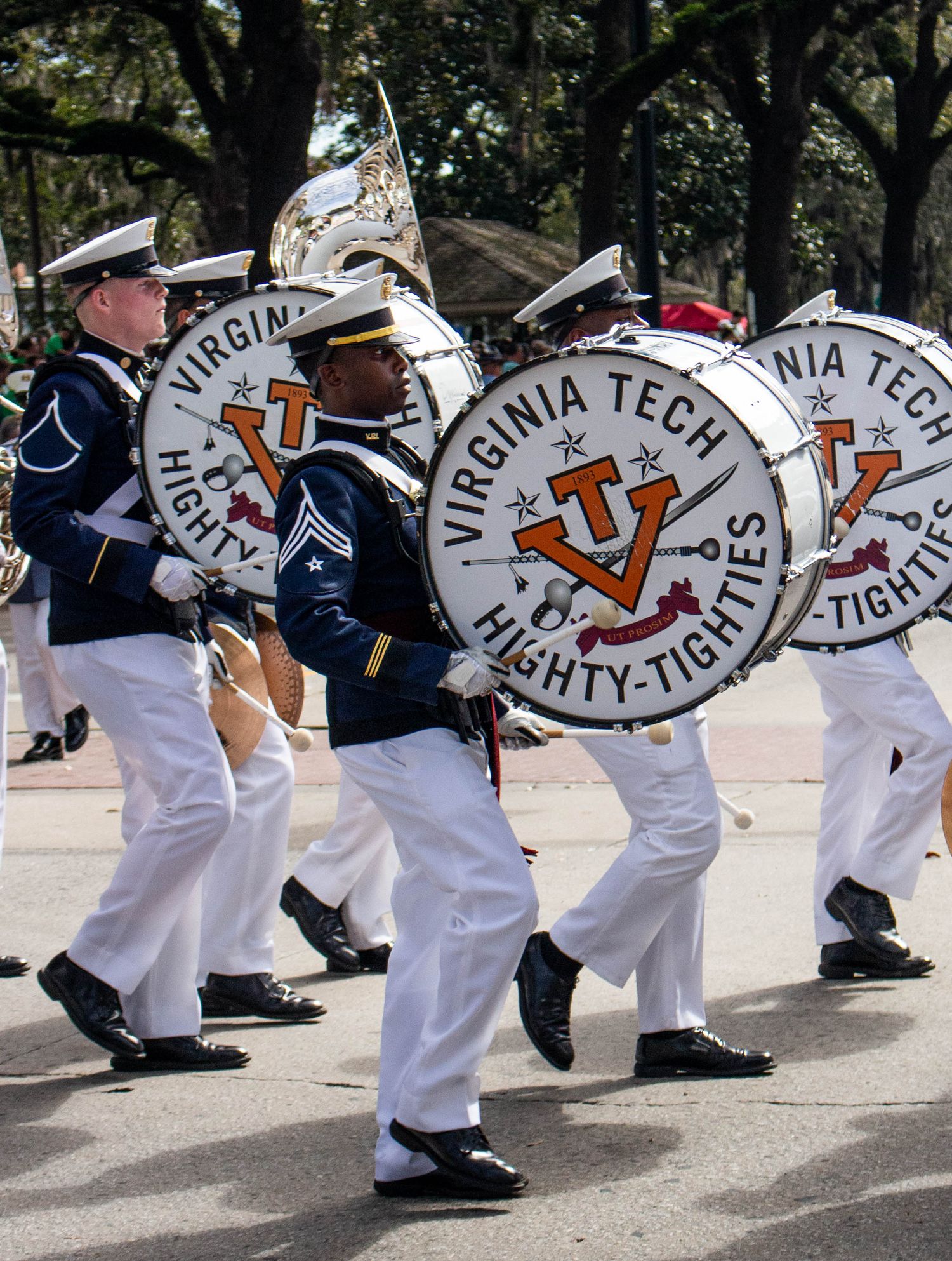 Virginia Tech marching band members carrying large bass drums during a performance.