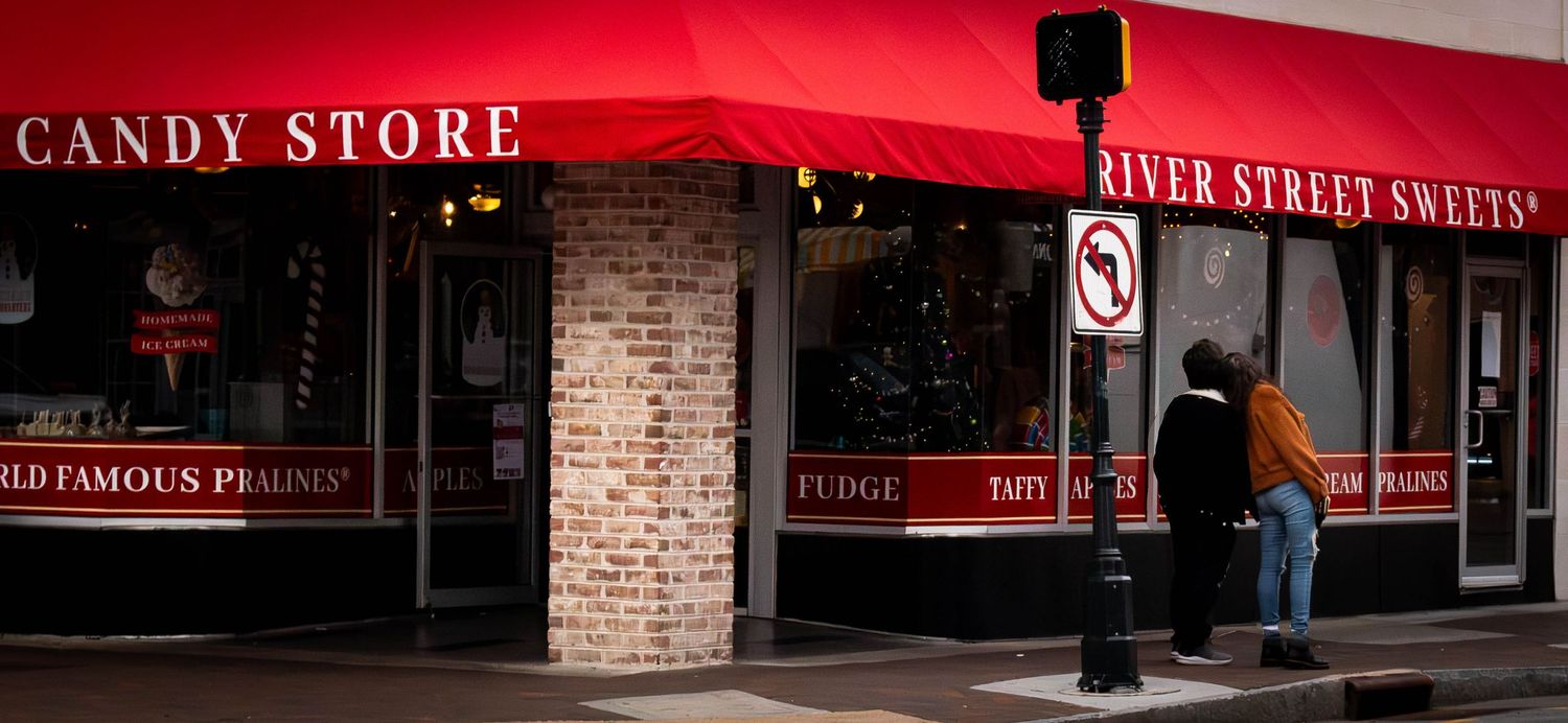 Red awning over candy store entrance with brick facade.