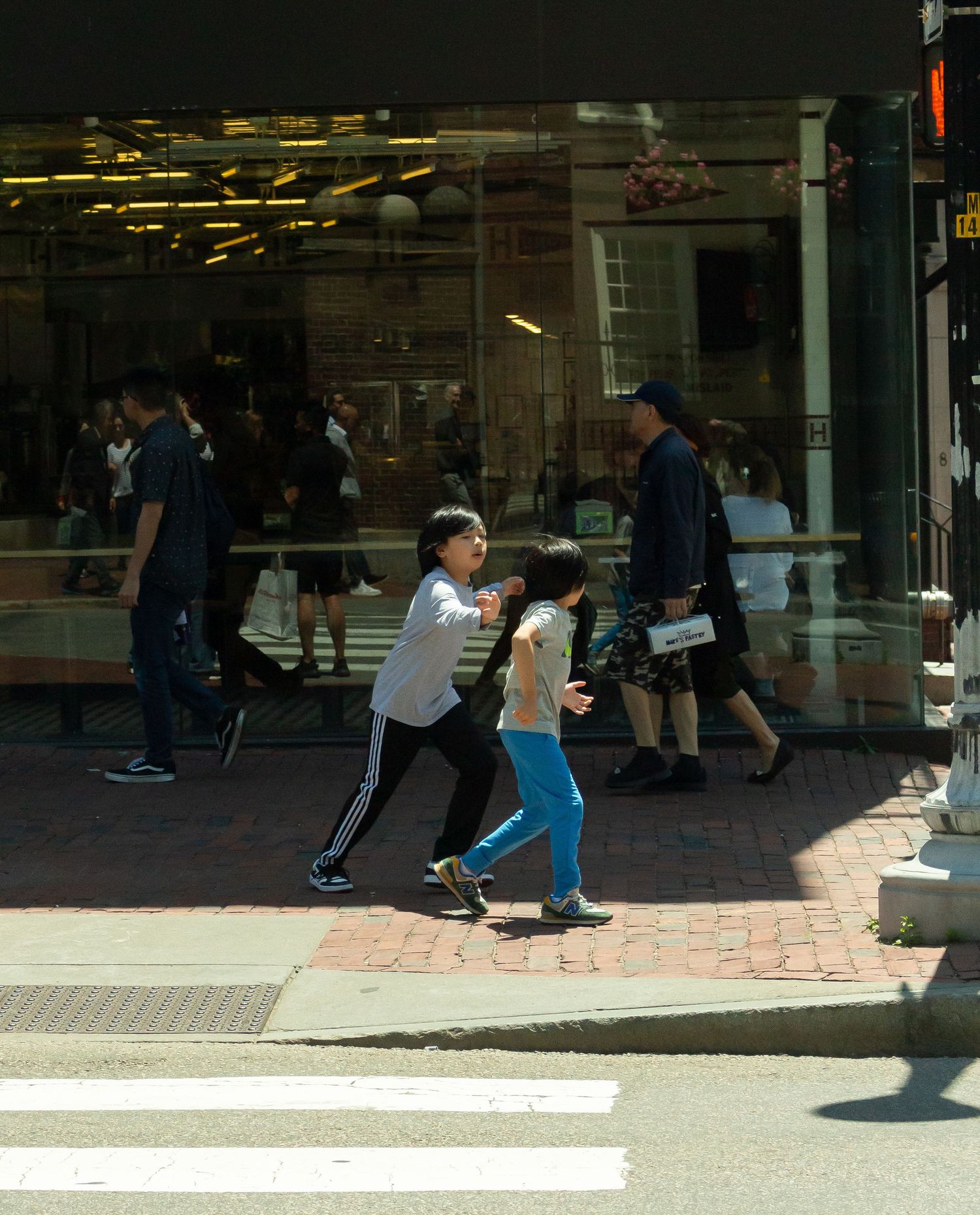 Children play on a sidewalk outside a storefront in an urban setting.