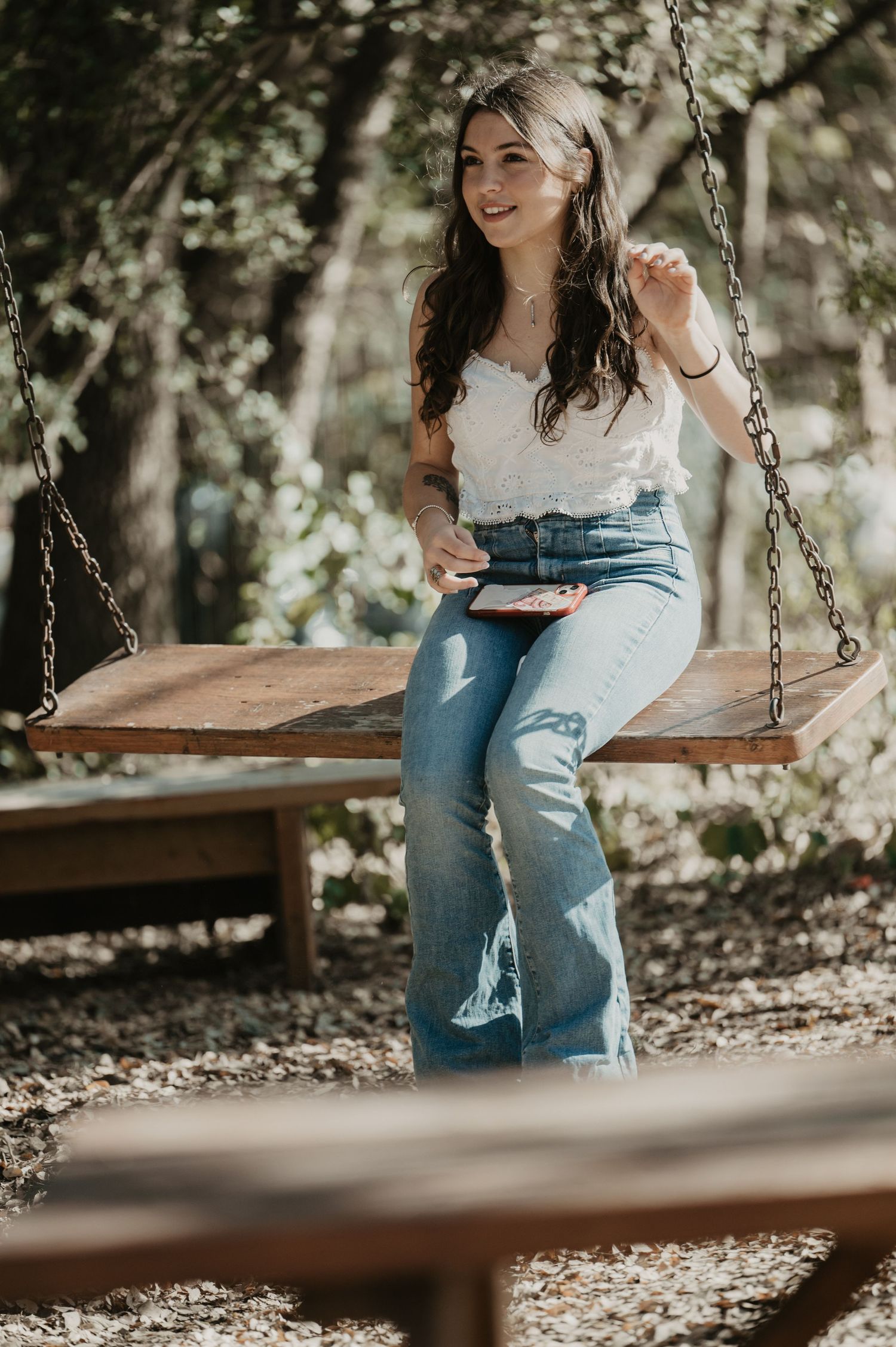 Casual portrait on wooden swing in dappled sunlight.