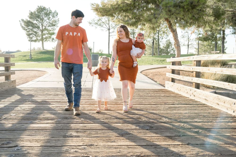 Parents swinging child between them while walking on a wooden boardwalk.