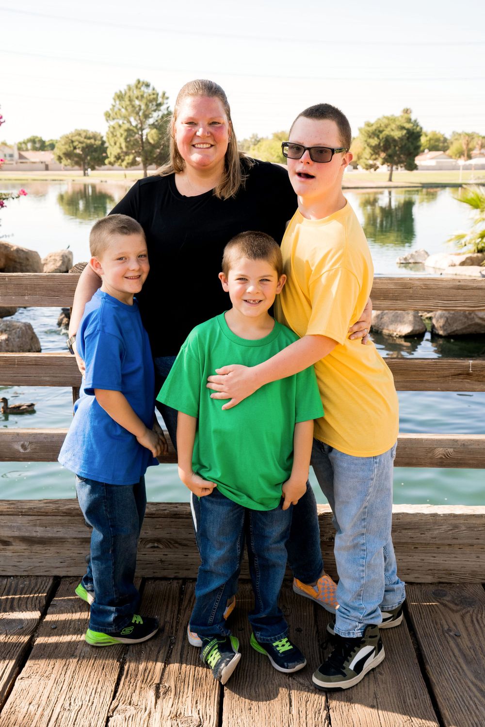 Group in coordinated casual outfits poses together on wooden deck overlooking water.