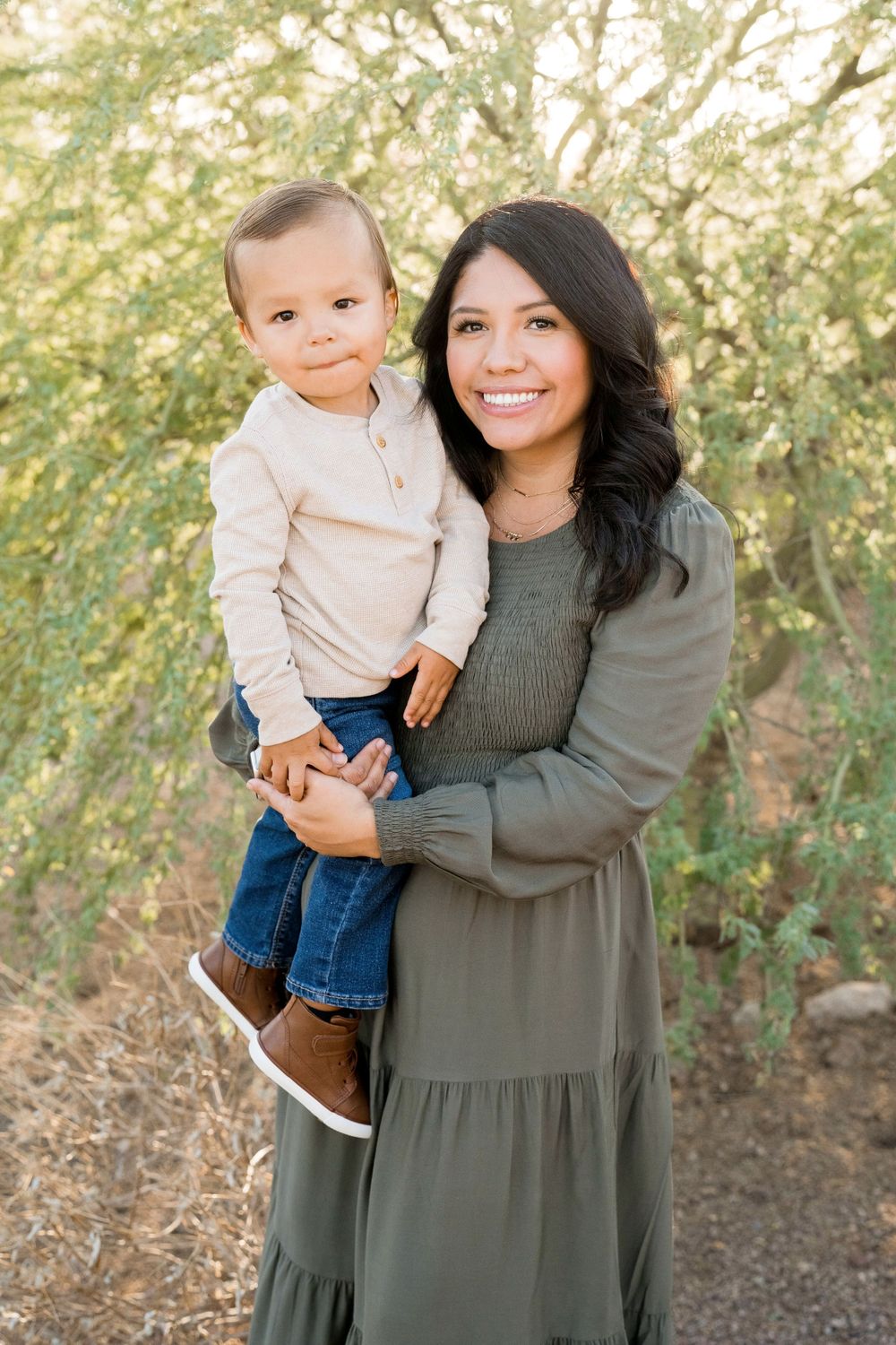 Parent and toddler posing for a portrait against a soft natural background.