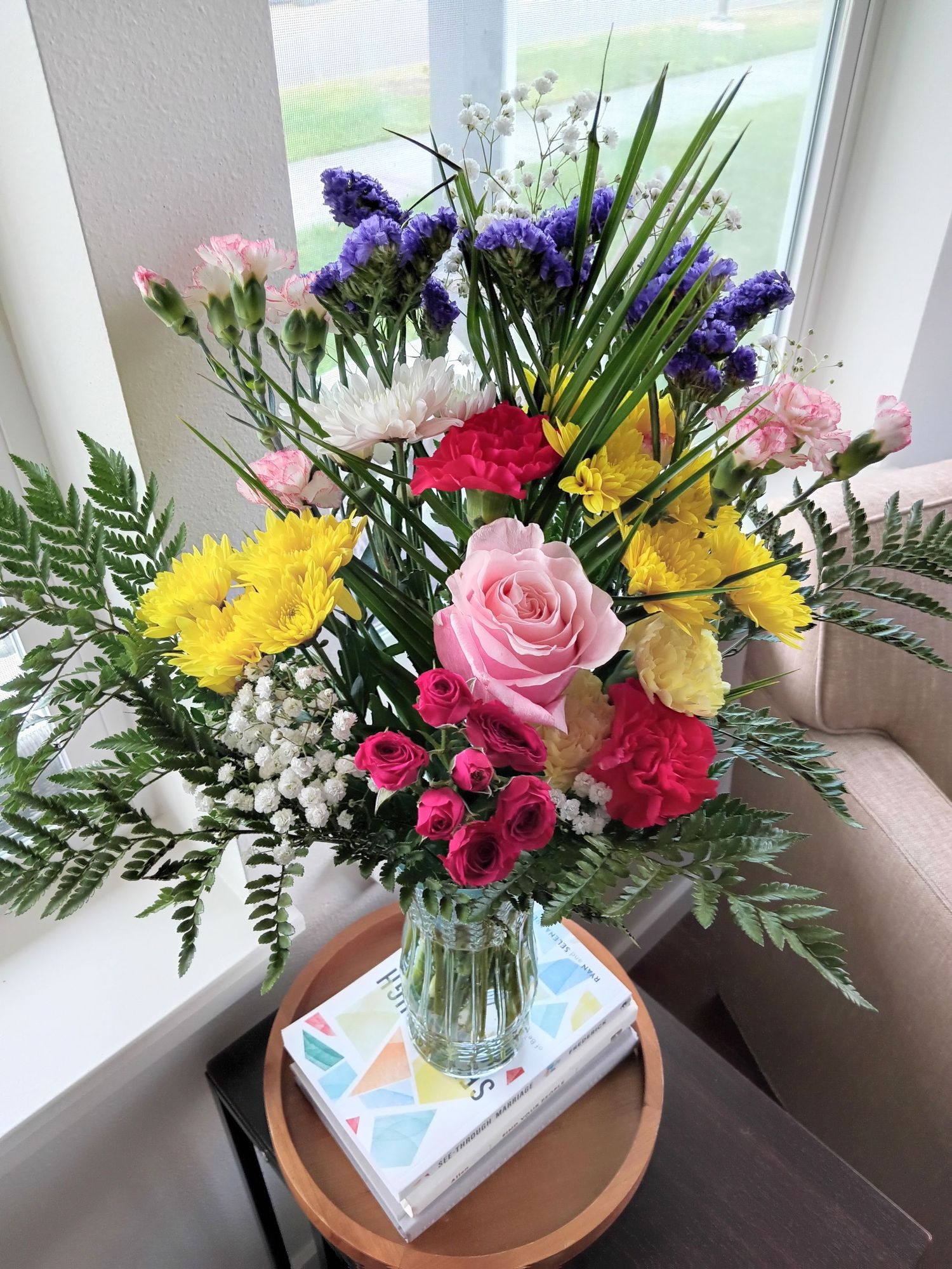 Colorful flower arrangement with roses, carnations and baby's breath in a glass vase.
