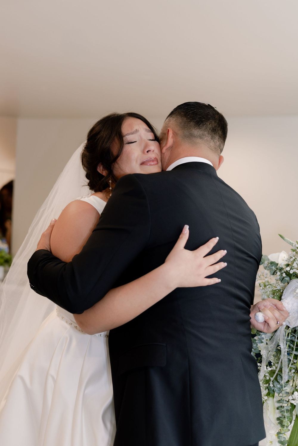 Emotional first look moments captured between bride and father in formal wedding attire.