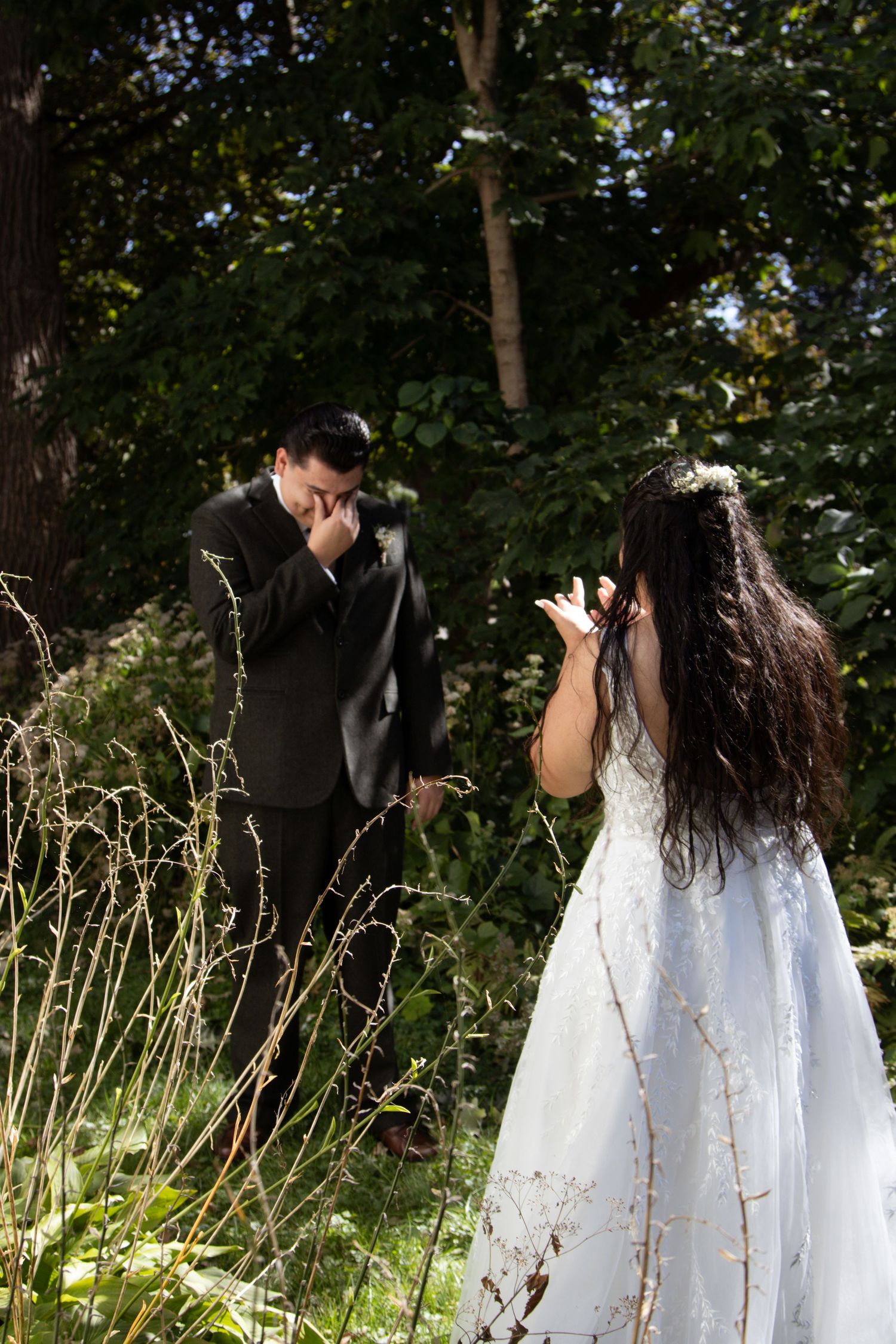 Bride and groom having an emotional first look moment in a garden setting.
