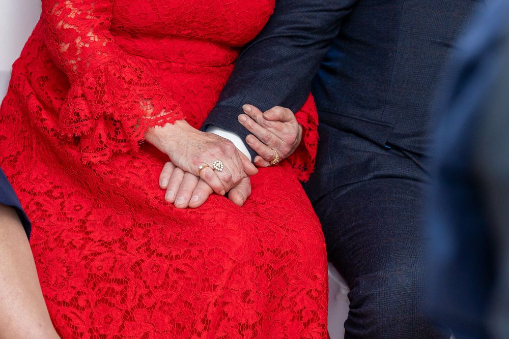 A close-up view of a couple's hands intertwined, wearing wedding rings.