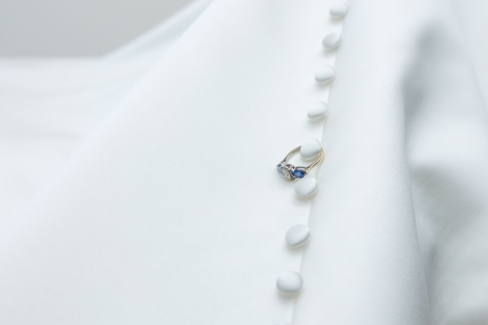 A close-up image of a pearl necklace with a small pendant against a soft, blurred background.