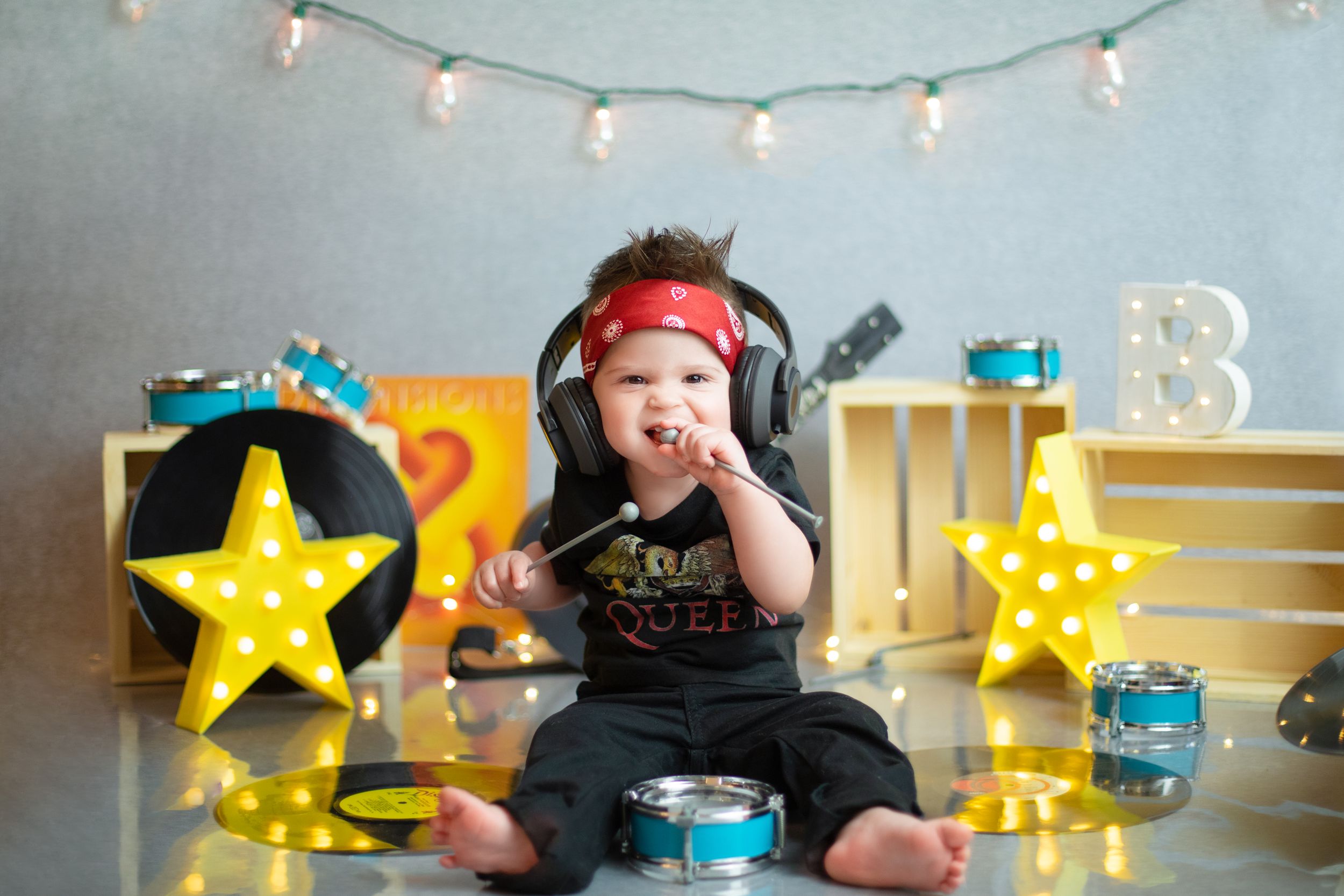 Small child sitting with headphones among vinyl records, lit star decorations and turquoise gift boxes.