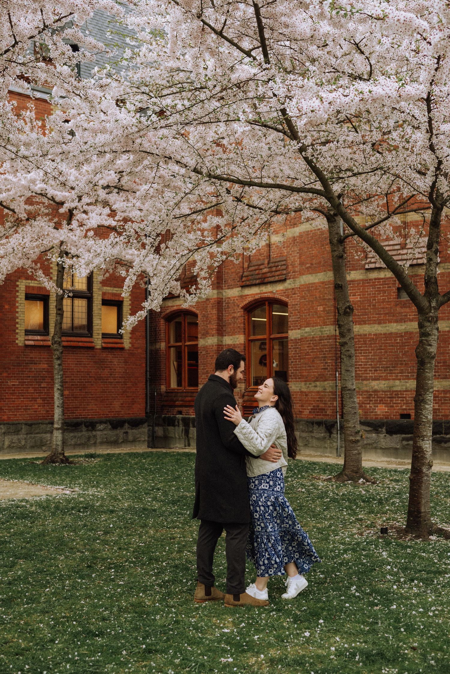 Happy couple after a marriage proposal in the Rijksmuseum garden under blooming cherry trees in Amsterdam