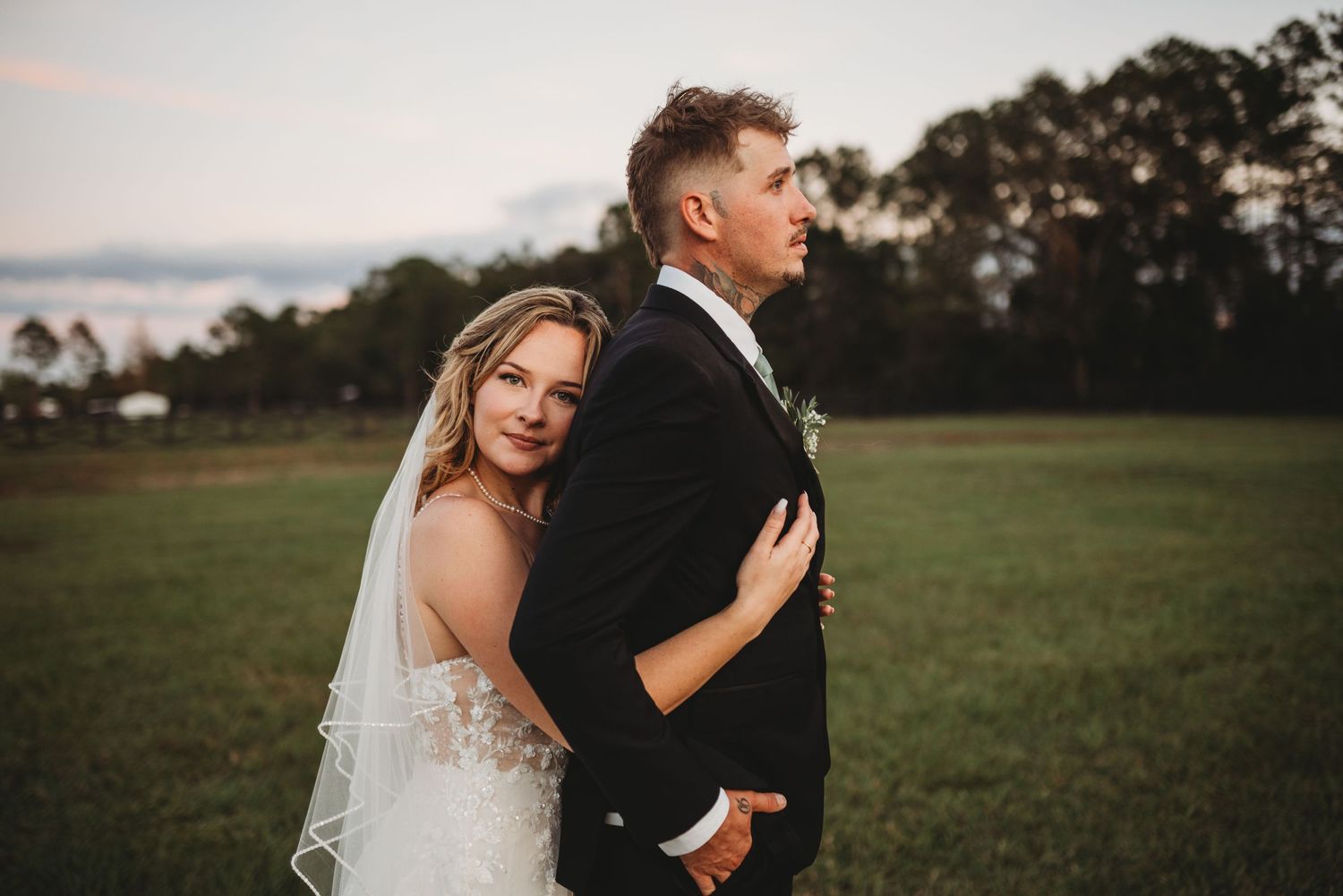 Sunset wedding portrait in an open field with mountain backdrop.