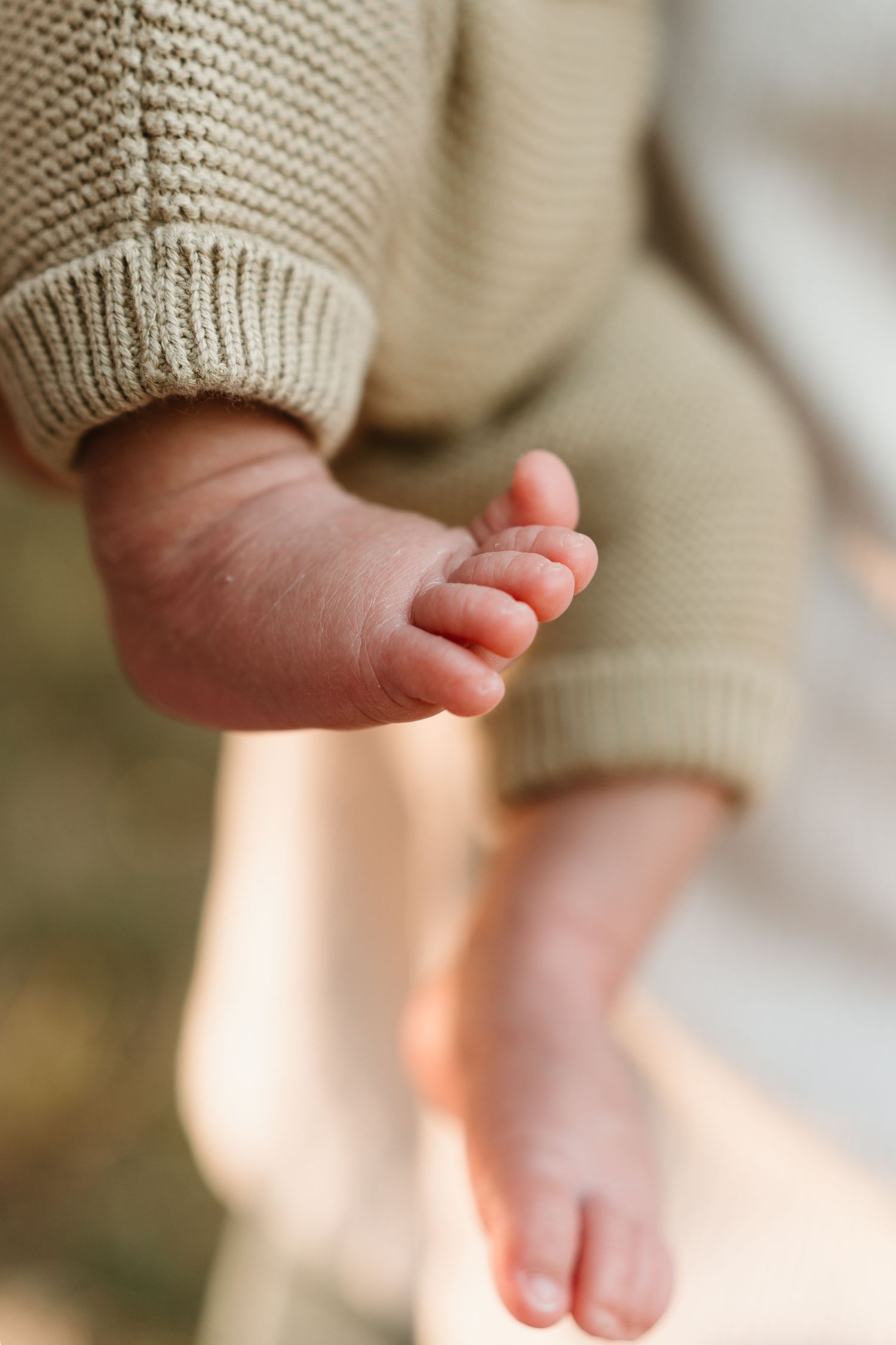Close-up detail shots of tiny baby feet in a knit sweater.