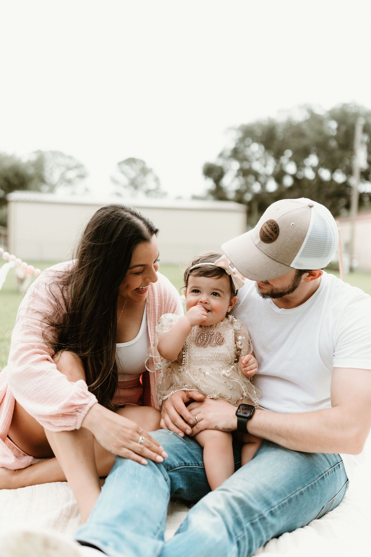 Family sharing tender moments together during outdoor photo session on grass.