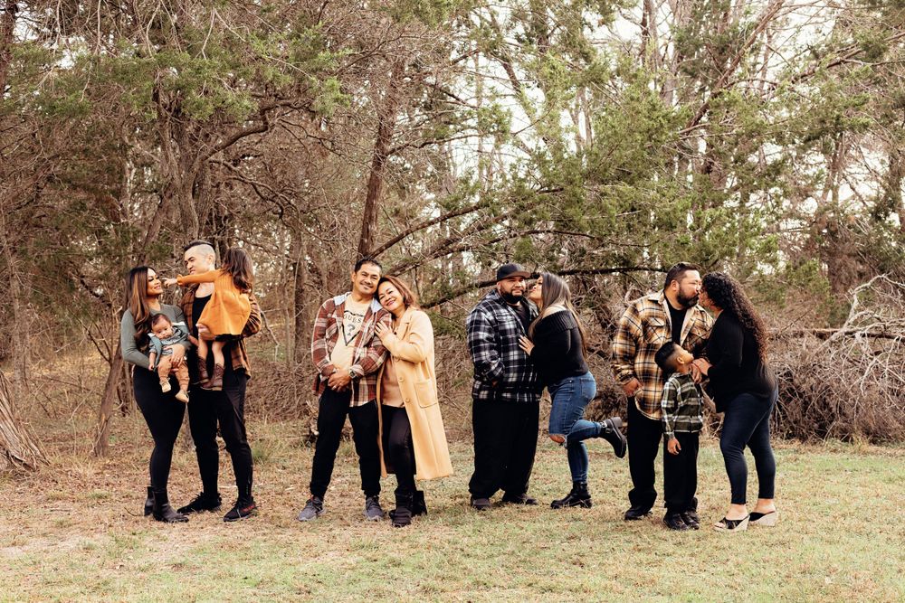 A group of photographers with cameras stand in a wooded outdoor setting ready to take pictures.