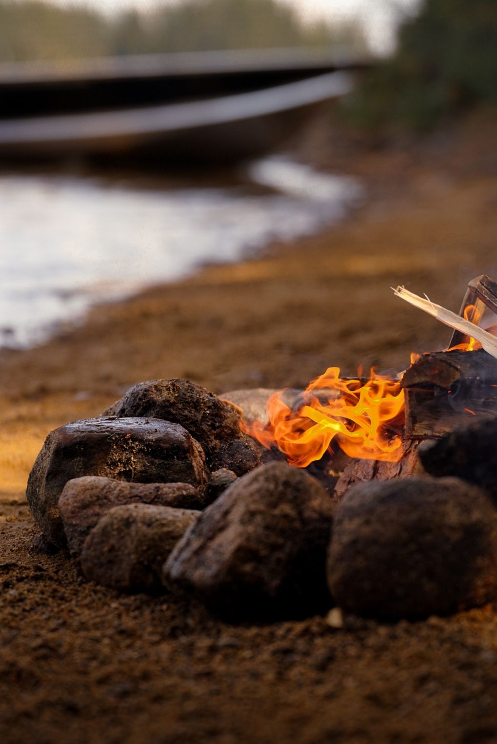 Burning charcoal emits bright orange flames against a dark background in a close-up shot.
