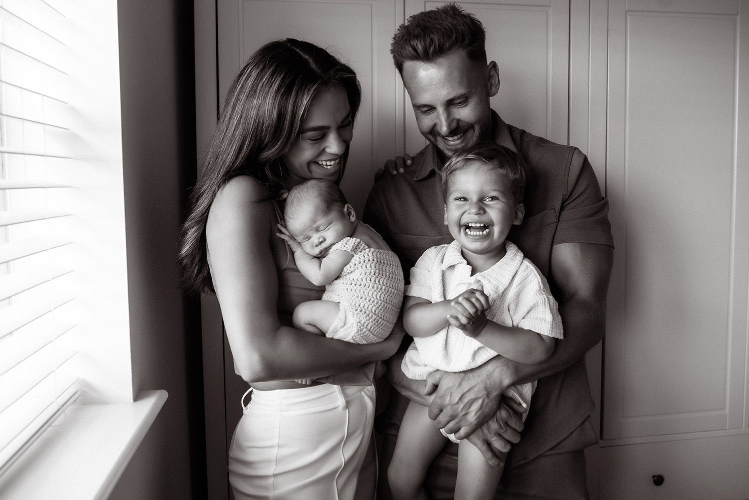 A series of black and white photographs showing intimate family moments with a baby in various candid poses.