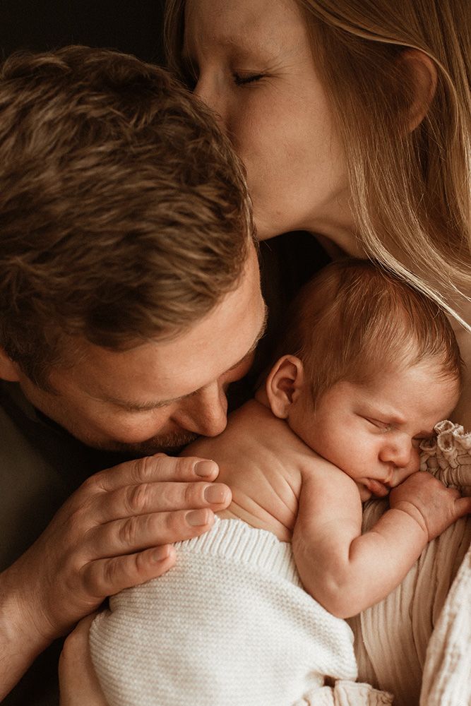 A tender sequence of parent and baby snuggling close together in warm, intimate moments.