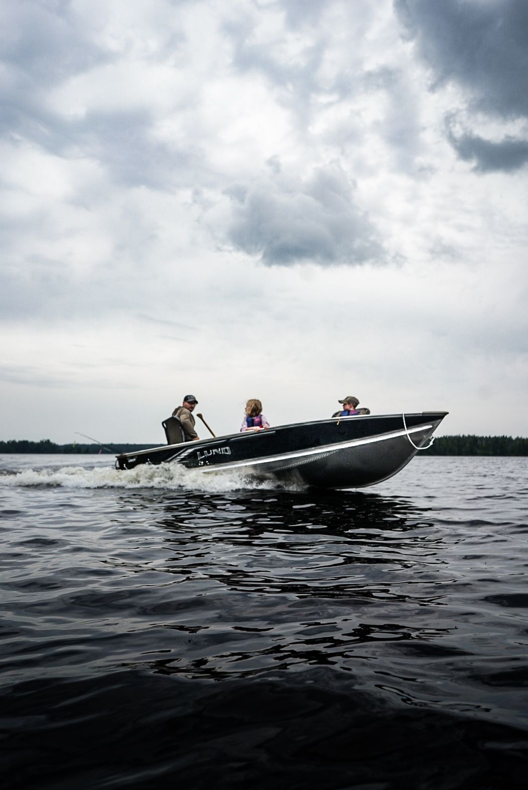 Black speedboat cutting through dark waters on an overcast day.