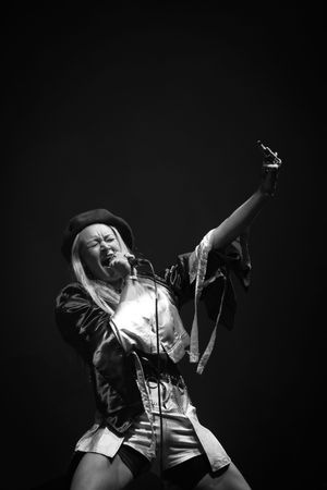 Black and white performance photos show a singer on stage in dramatic poses against a dark background.