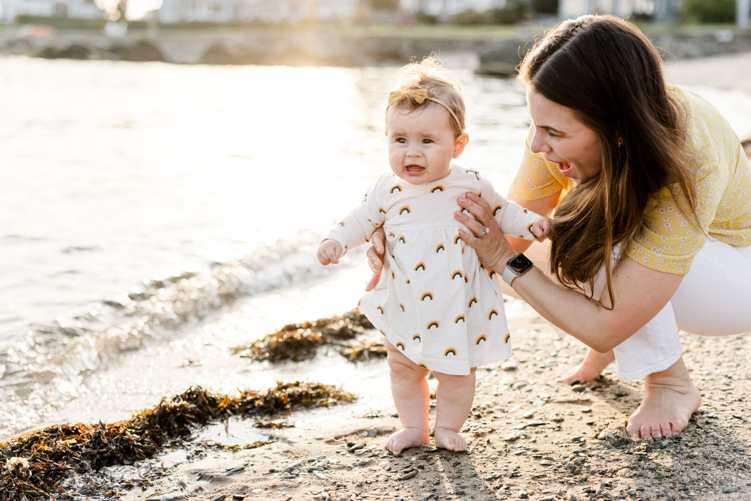 Sweet moment at the beach with toddler in floral dress exploring the shoreline.
