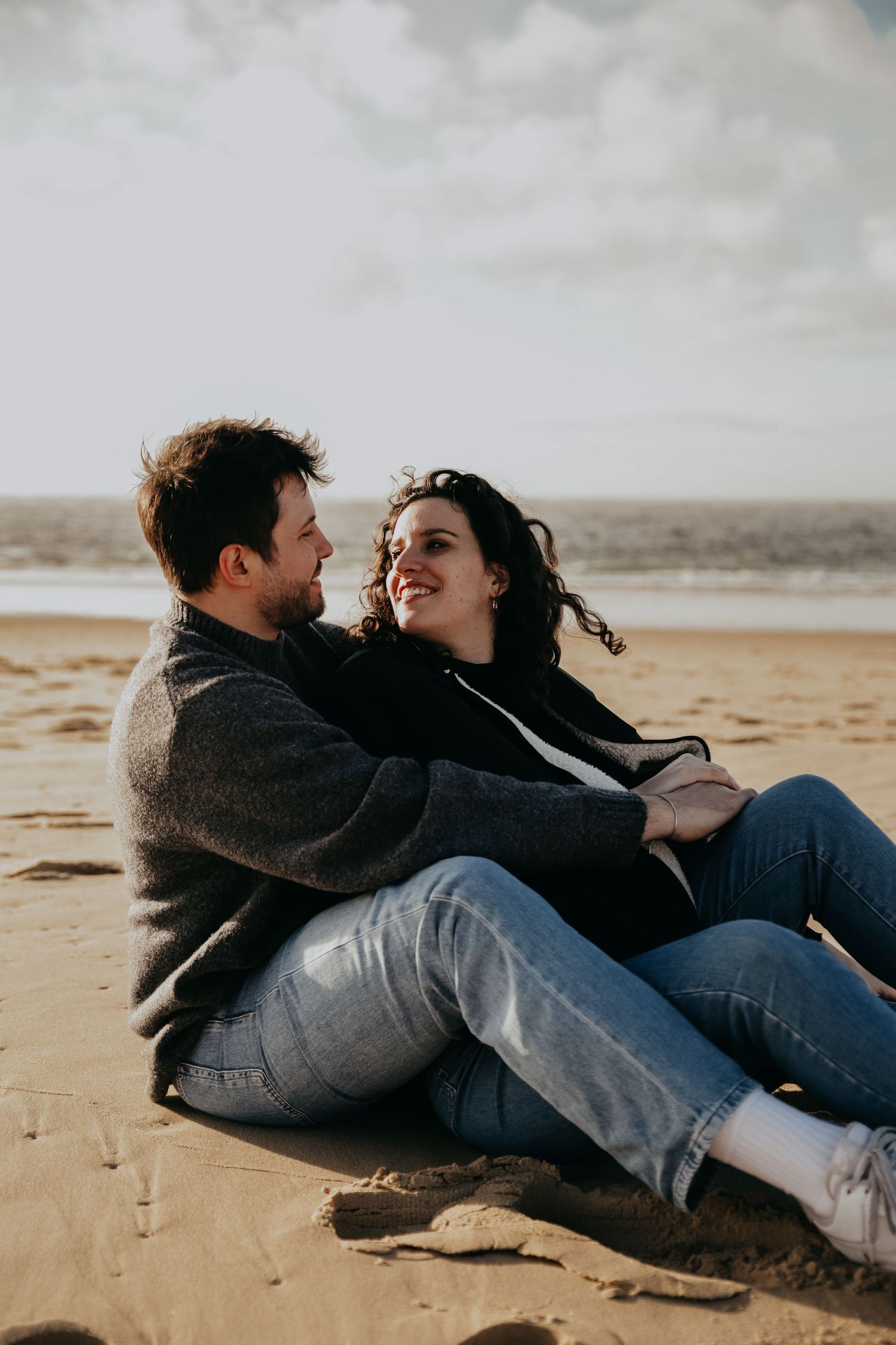 A couple shares a playful moment while relaxing on a sandy beach.