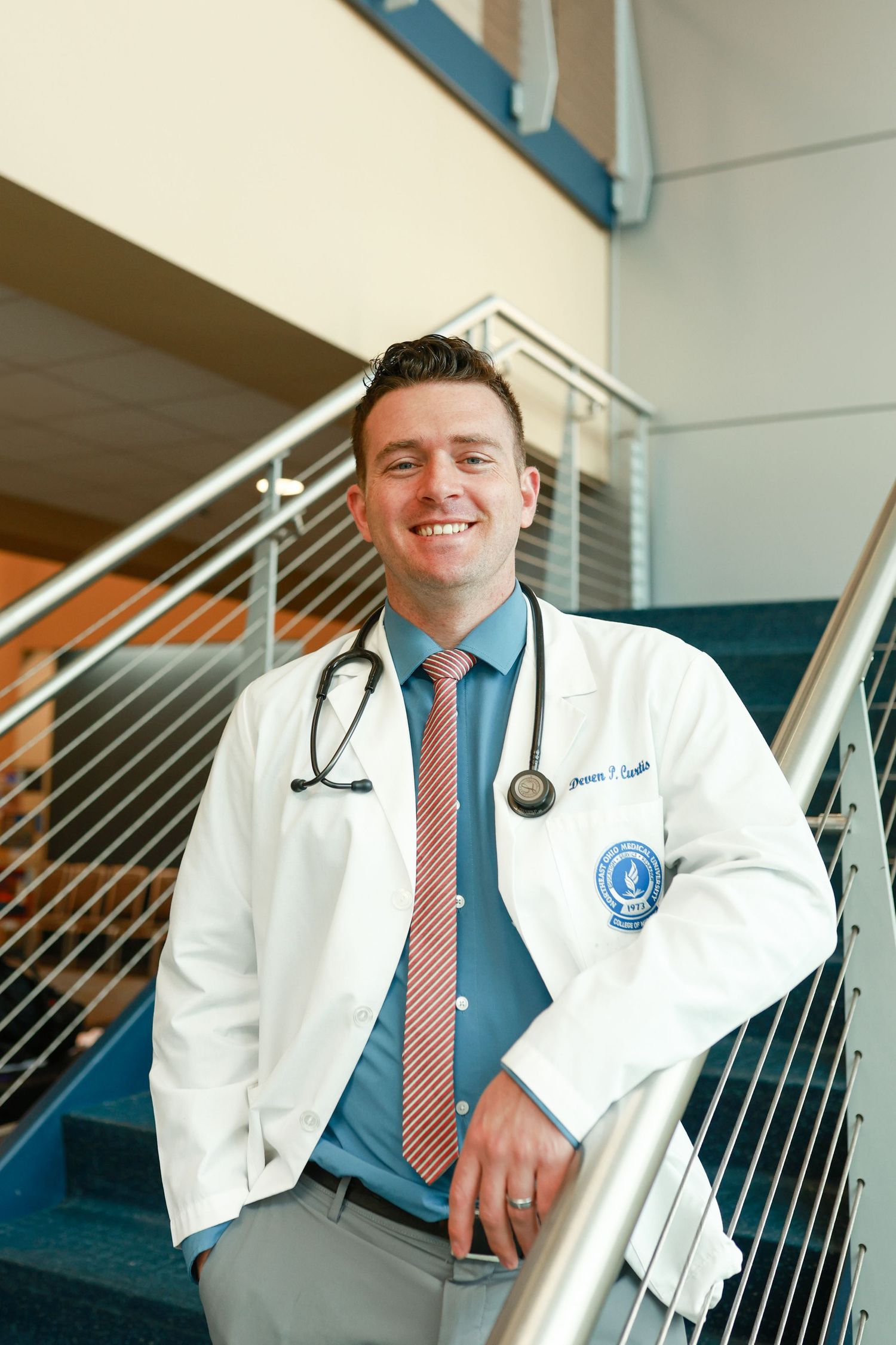 proud medical school graduate standing with stethoscope at Northeast Medical University in Rootstown, Ohio.