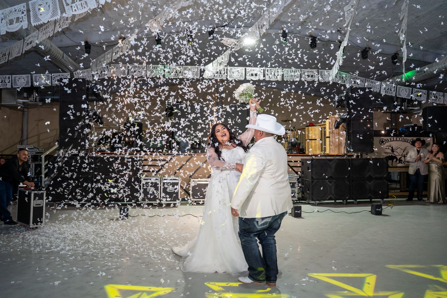 A couple dances together during their first dance as confetti falls around them at their wedding reception.