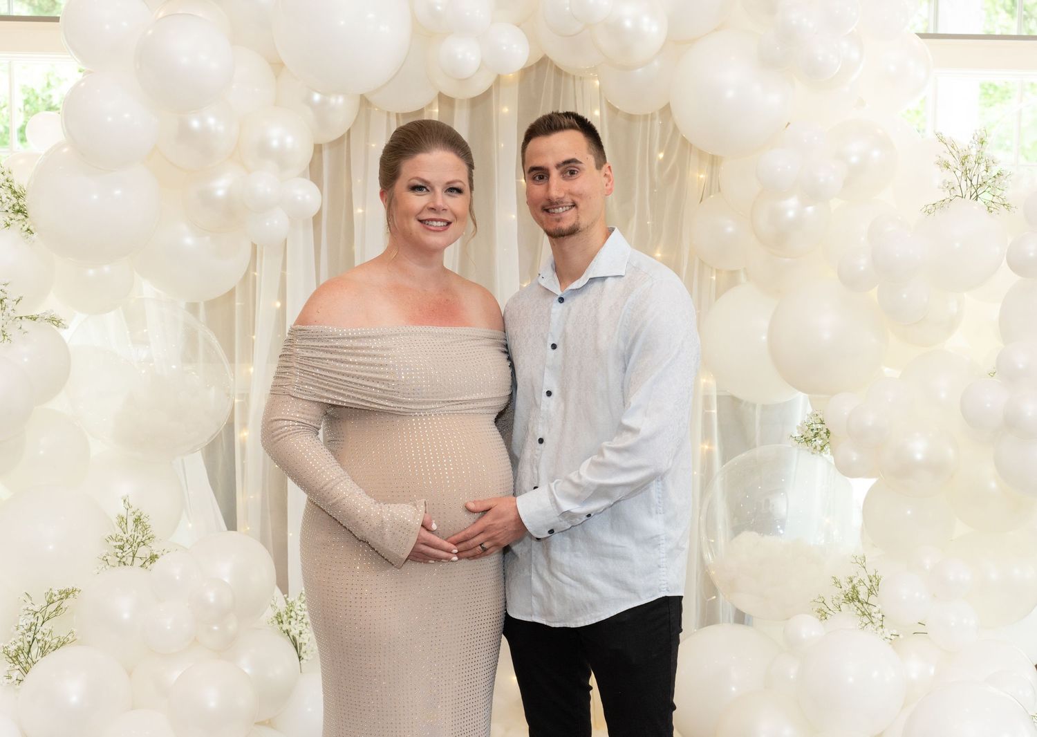 A formal photo against a white balloon wall and floral backdrop.