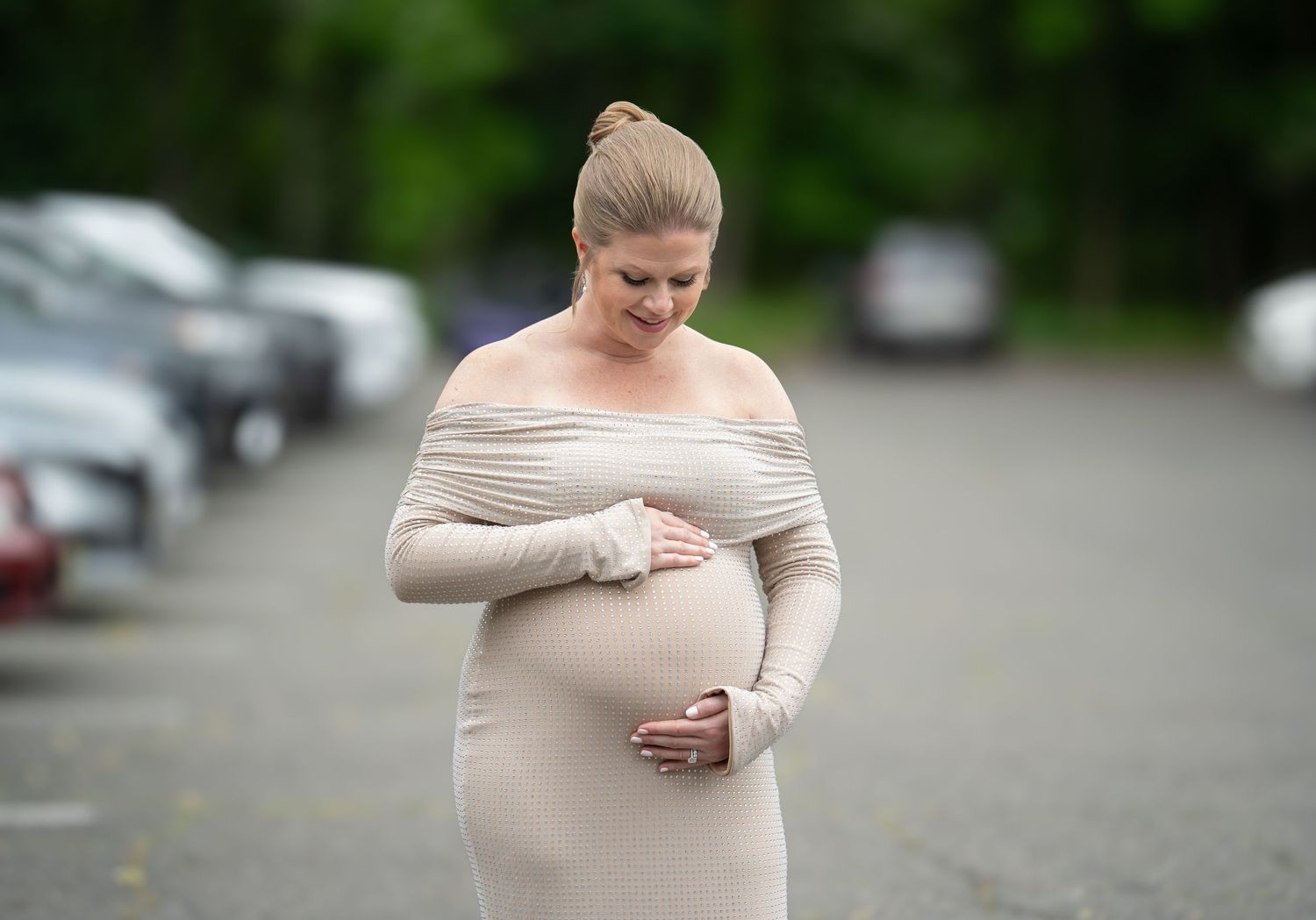 Maternity shoot beige off-shoulder dress standing outdoors.