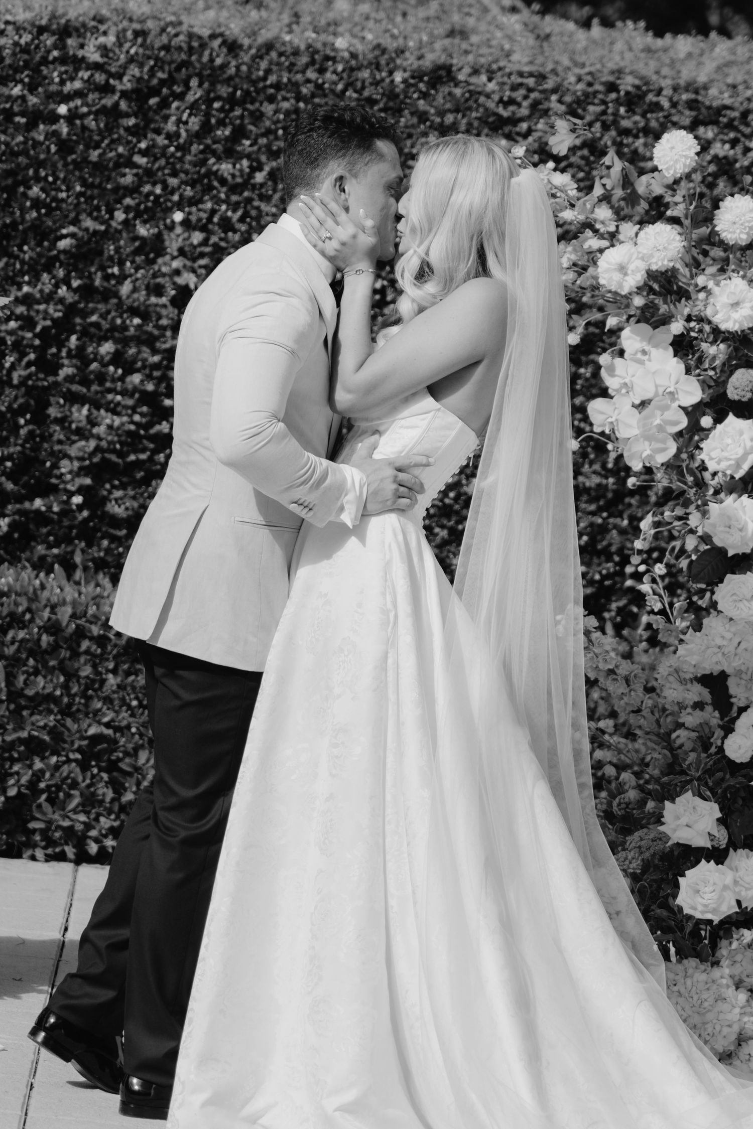 A romantic black and white wedding photo sequence showing a couple in tender embraces surrounded by garden flowers.