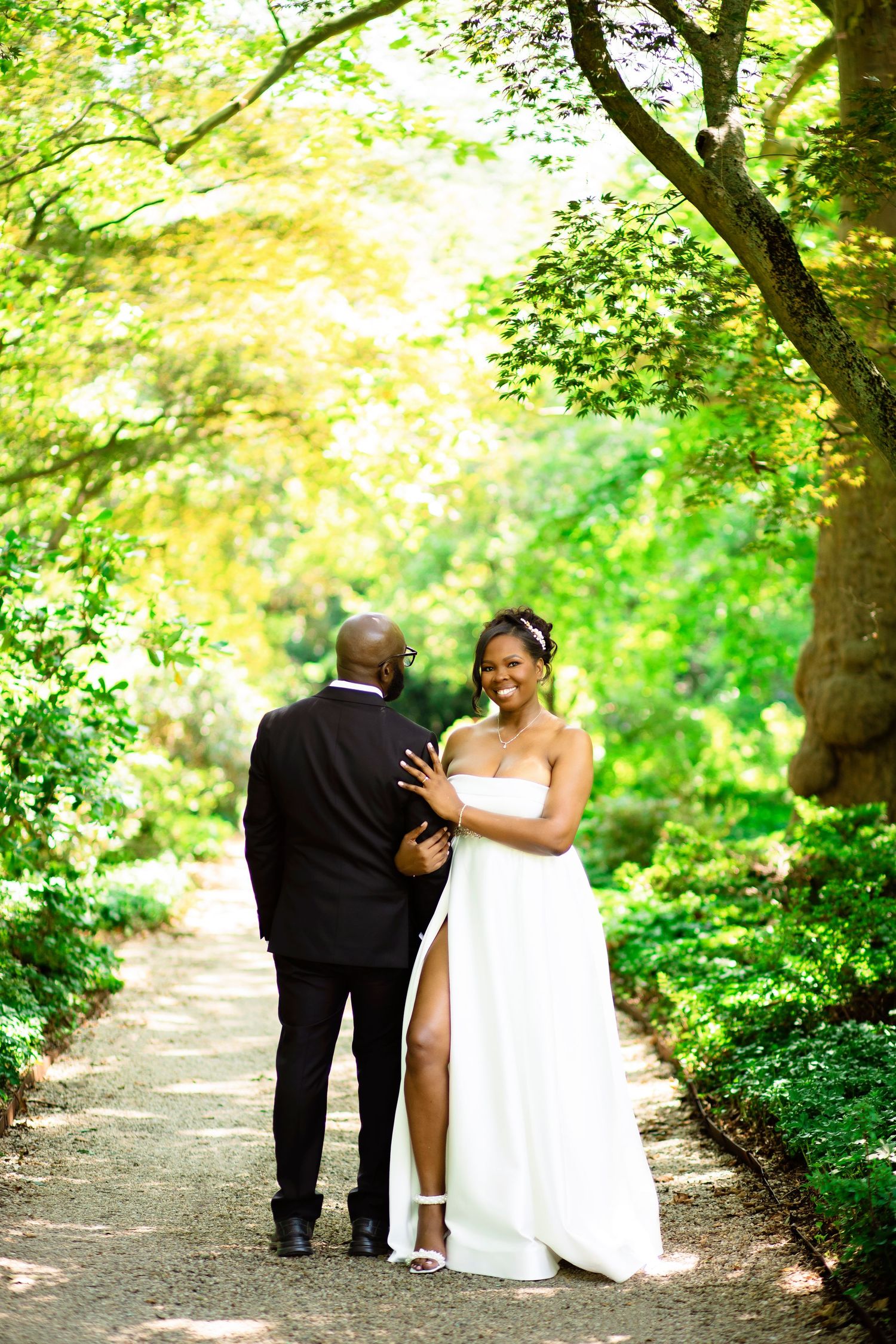 A romantic proposal scene set between rows of grapevines in a scenic vineyard with white flowers and a blanket.