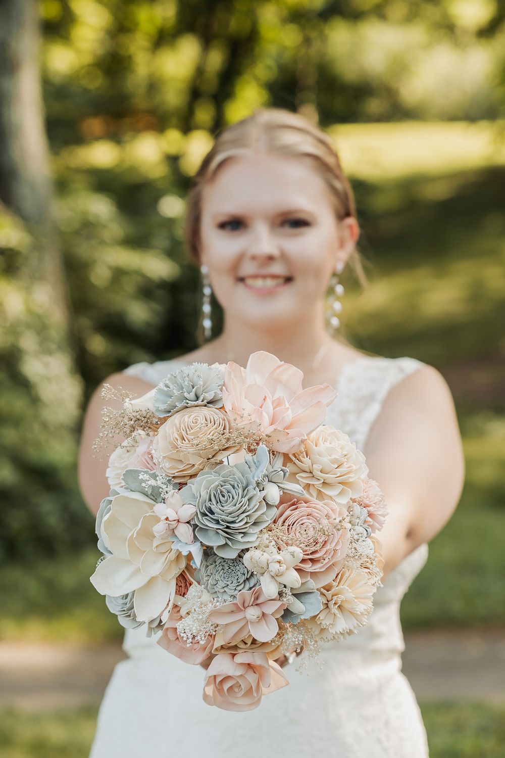 Beautiful bridal bouquet features blush roses and gray succulents in a romantic garden-inspired arrangement.