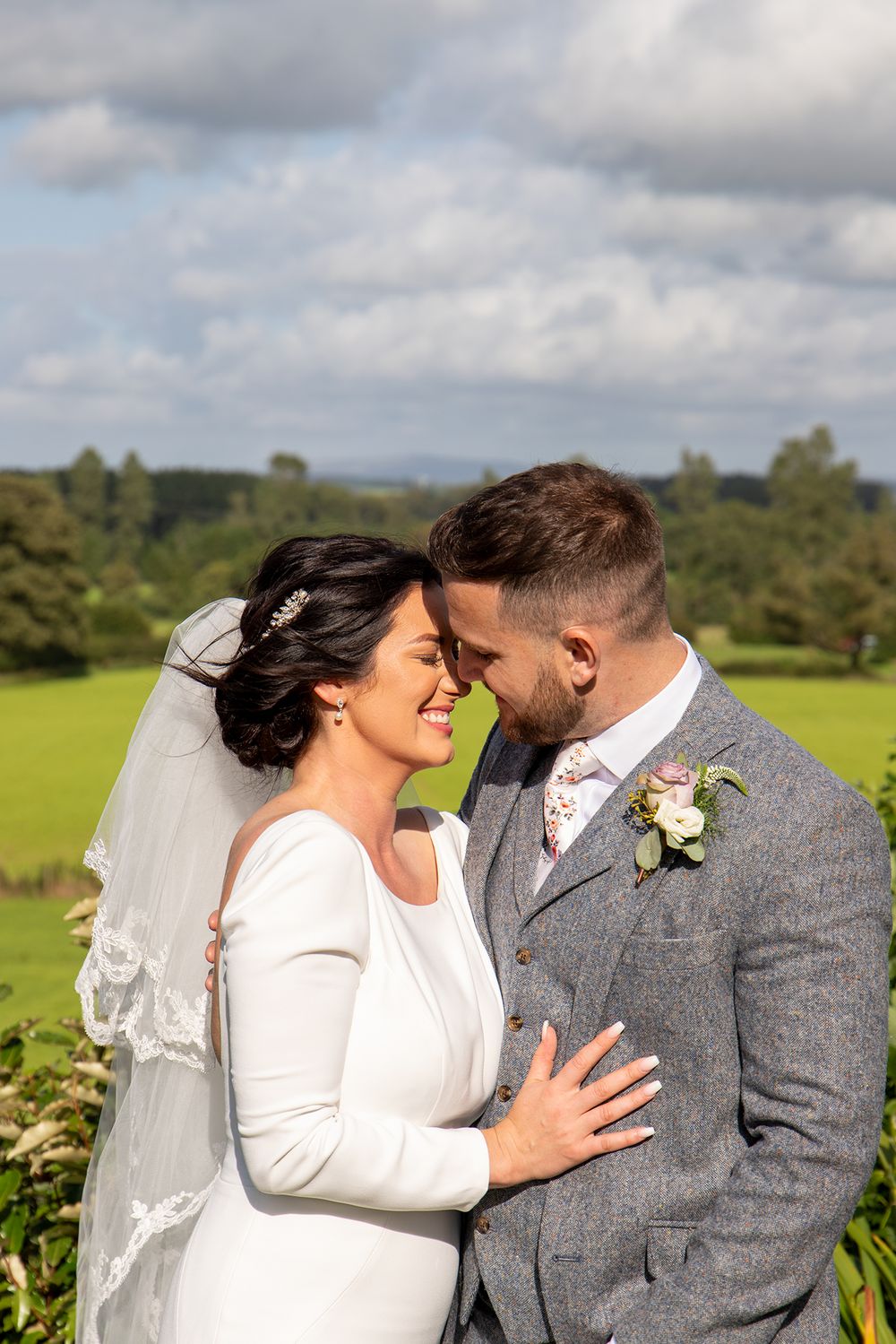 Wedding couple sharing joyful moments in a scenic countryside setting.