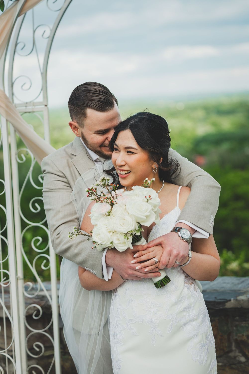 A joyful newlywed couple embraces while holding a white floral bouquet at the bluemont vineyard in virginia