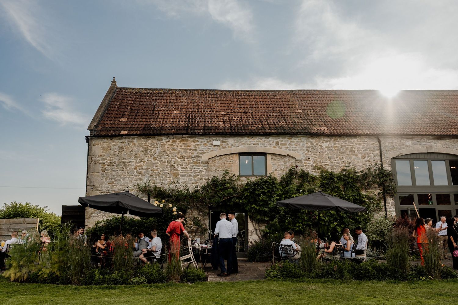 Panoramic view of rustic stone barn wedding venue under blue summer sky.