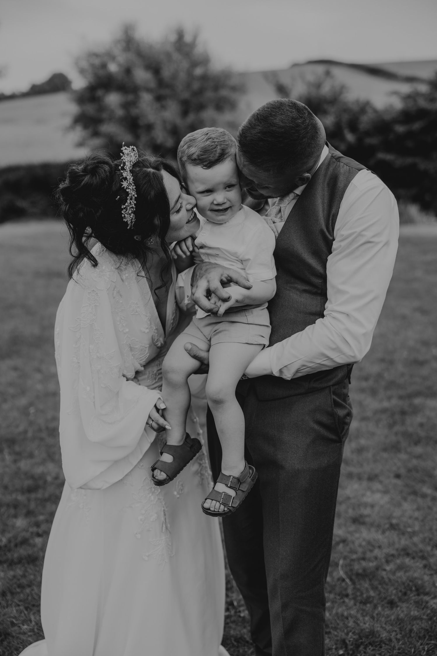 Black and white intimate family moment captured in an outdoor setting.