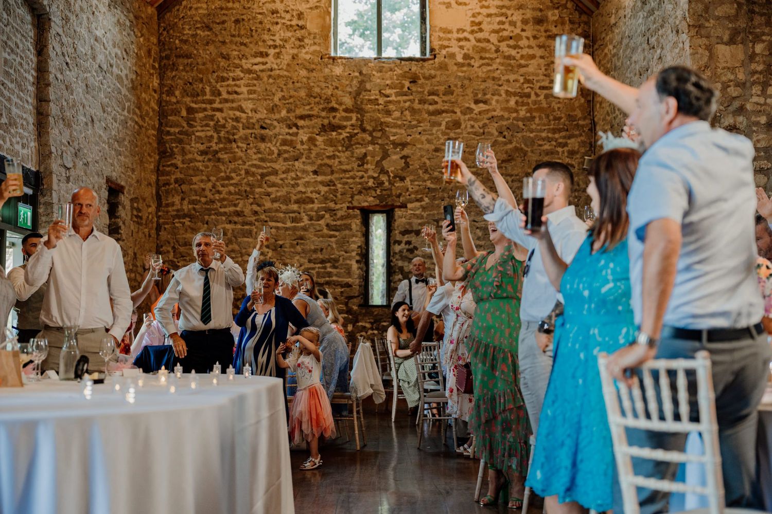 Interior of rustic stone venue with white chairs set up for wedding reception.