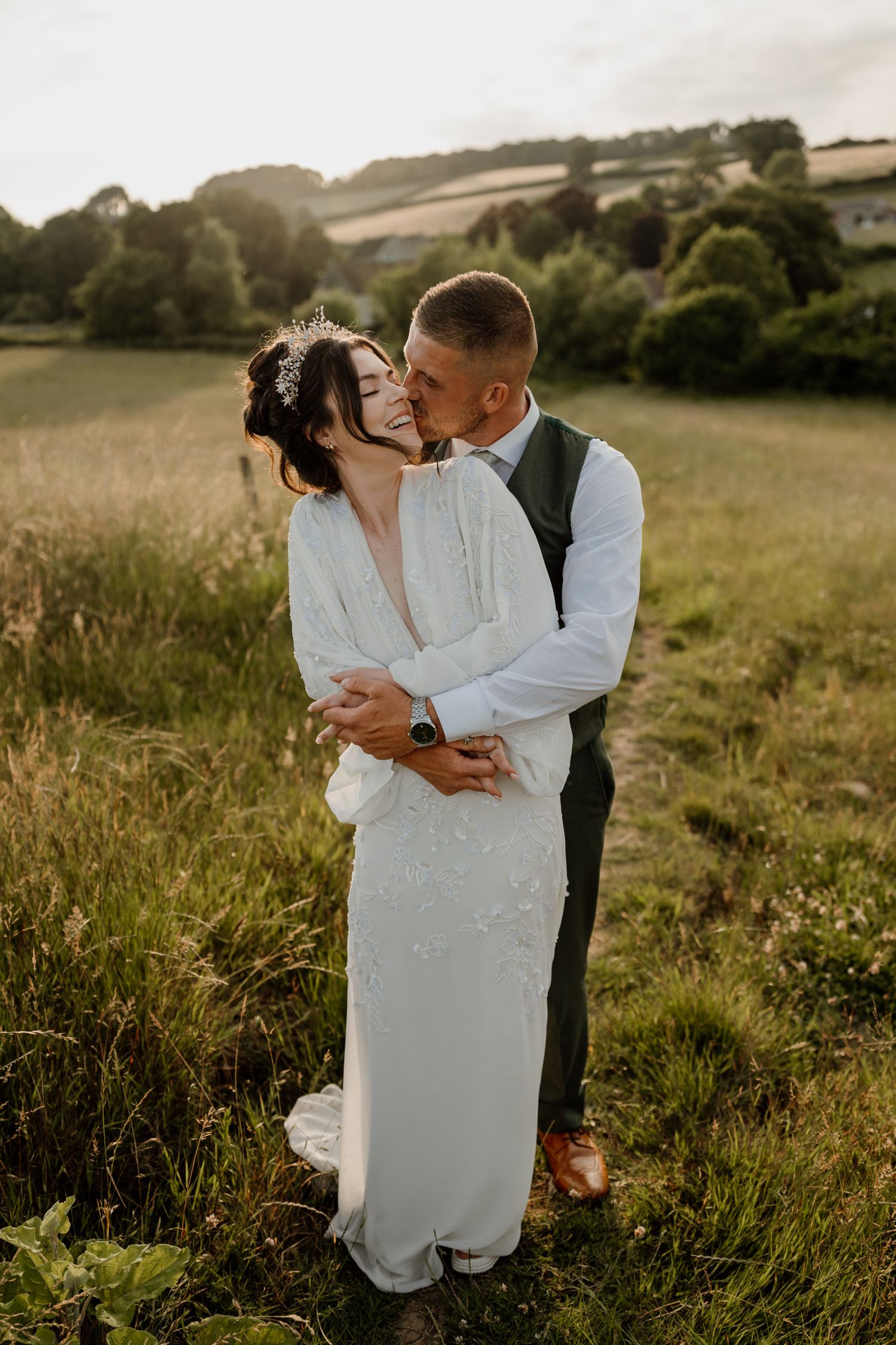 Romantic couple shares intimate moments in a sunlit meadow during their wedding photoshoot.