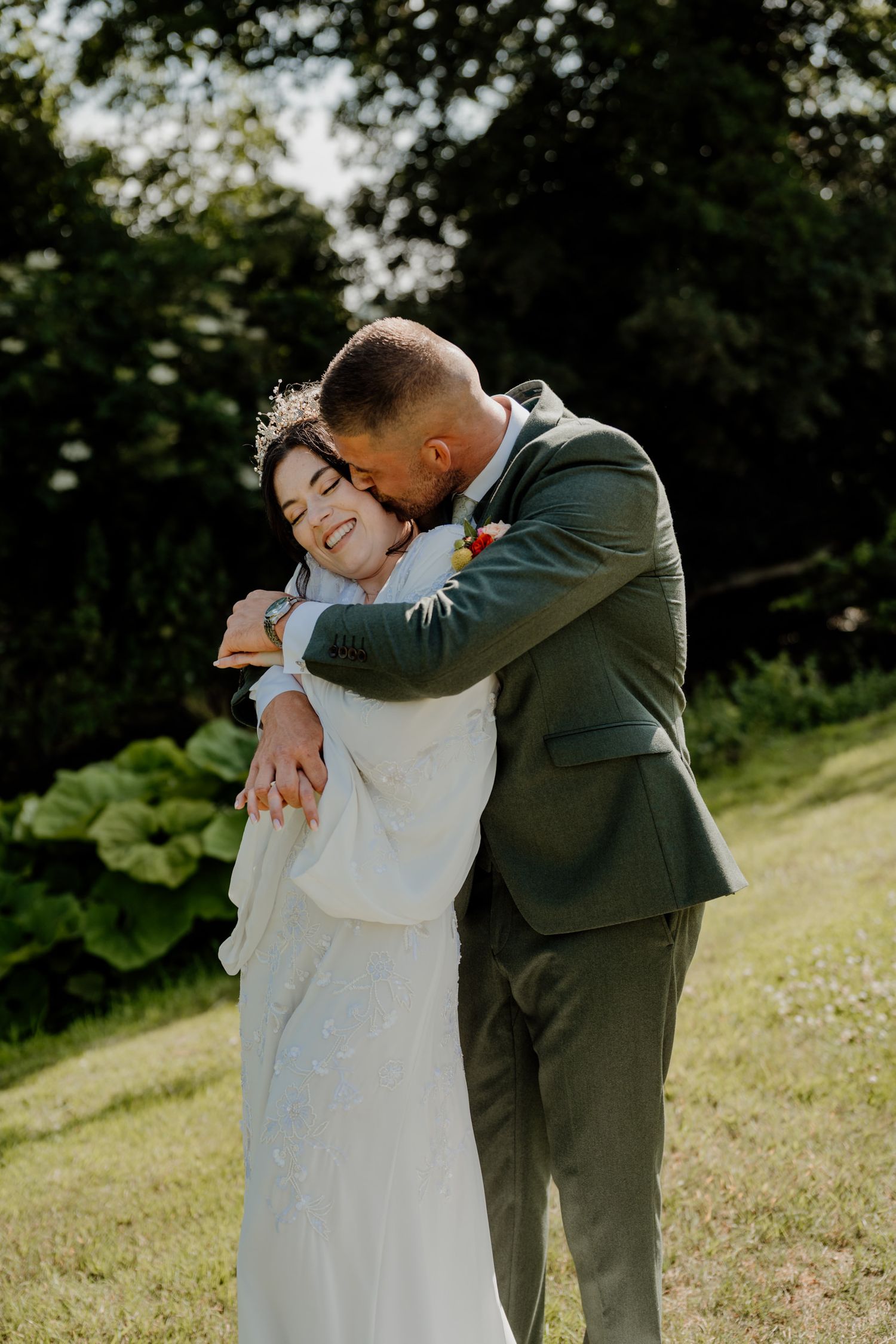 Couple embracing on a grassy hillside during an intimate moment.