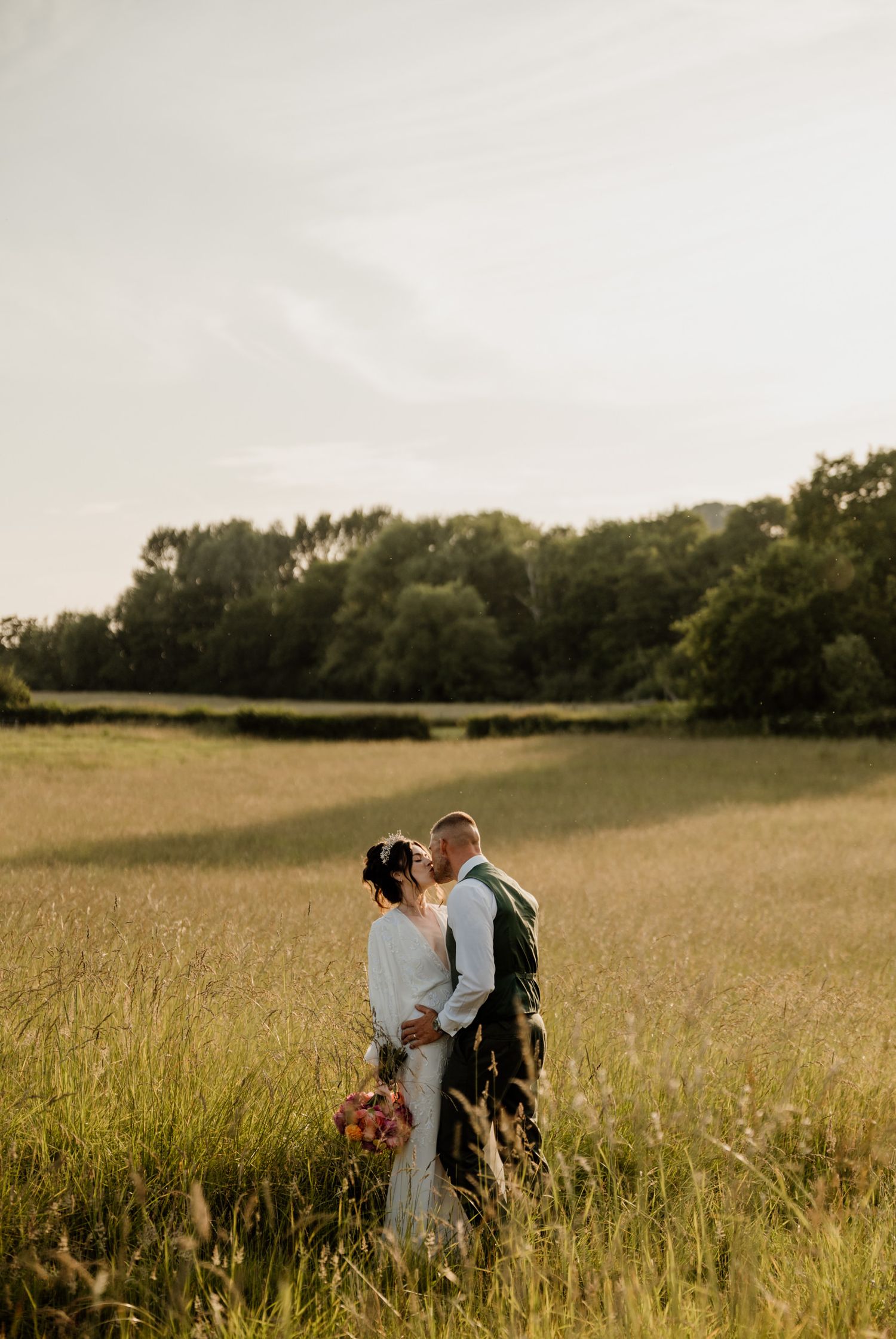 Romantic couple embracing in a golden sunset meadow during their wedding photoshoot.