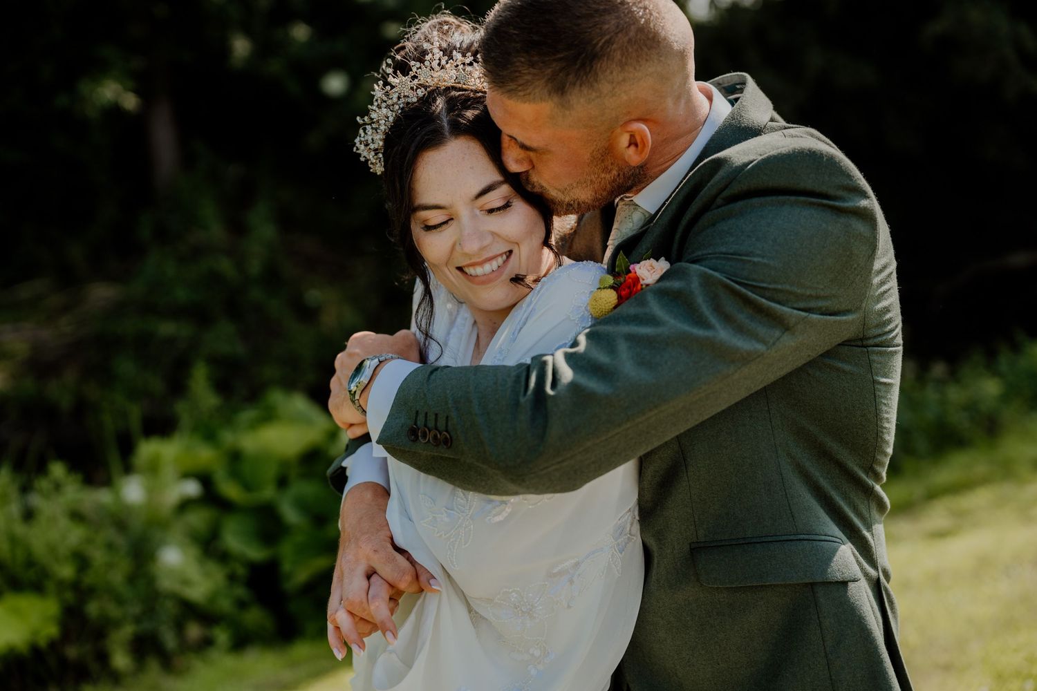 Romantic embrace captured in natural outdoor wedding setting.