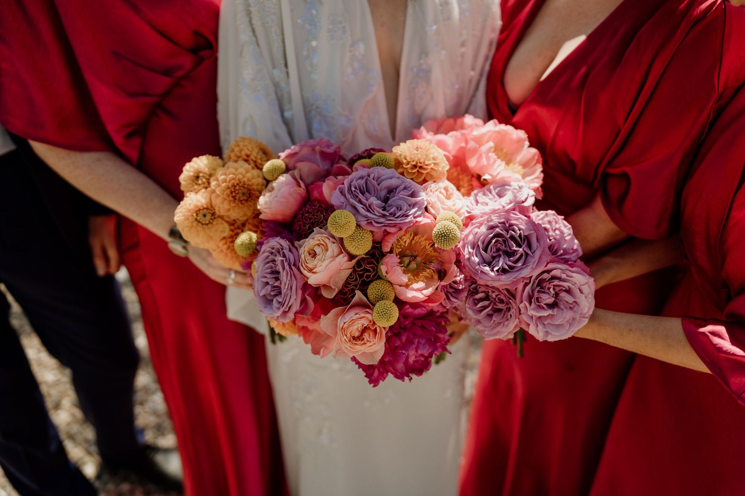 Close-up of pink and purple floral bouquet against red fabric.