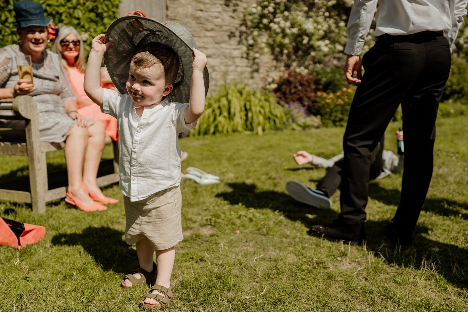 Wedding guests enjoying festivities on a sunny garden lawn.