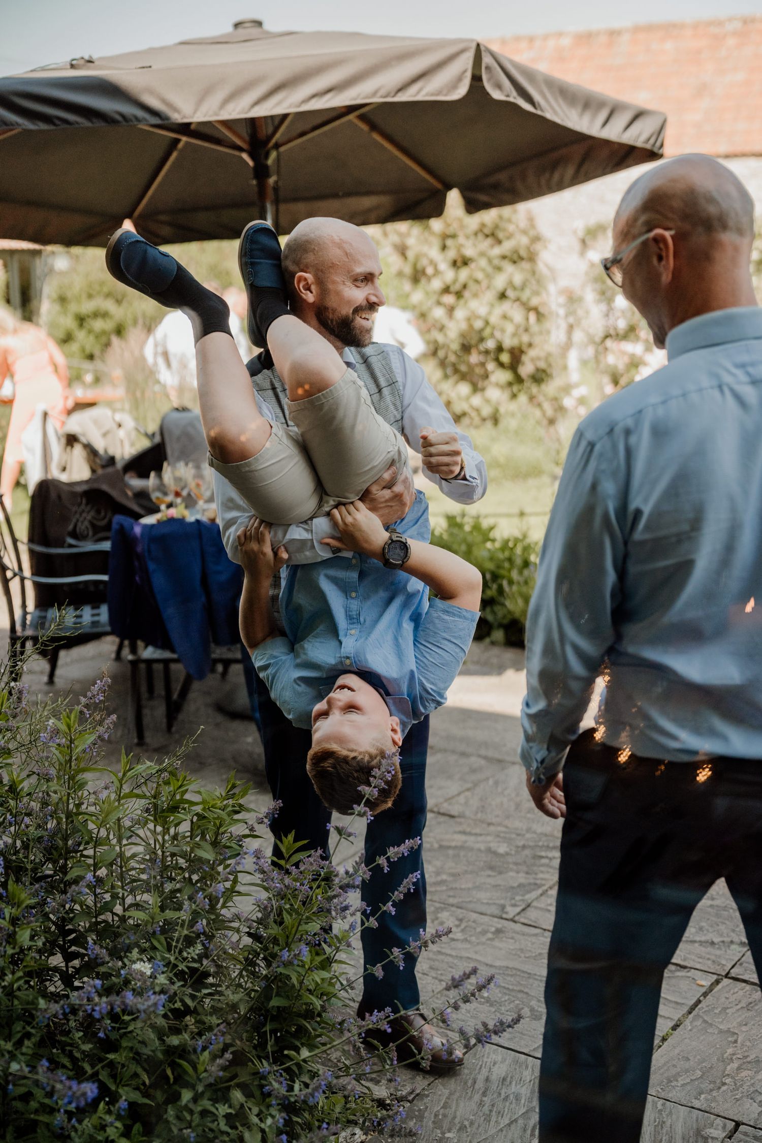 A sequence of people in blue outfits dancing together under an outdoor tent on a stone patio.