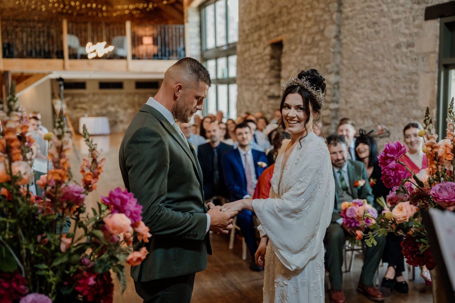 Wedding celebration in a rustic stone building venue decorated with string lights and floral arrangements at Priston Mill in Bath.