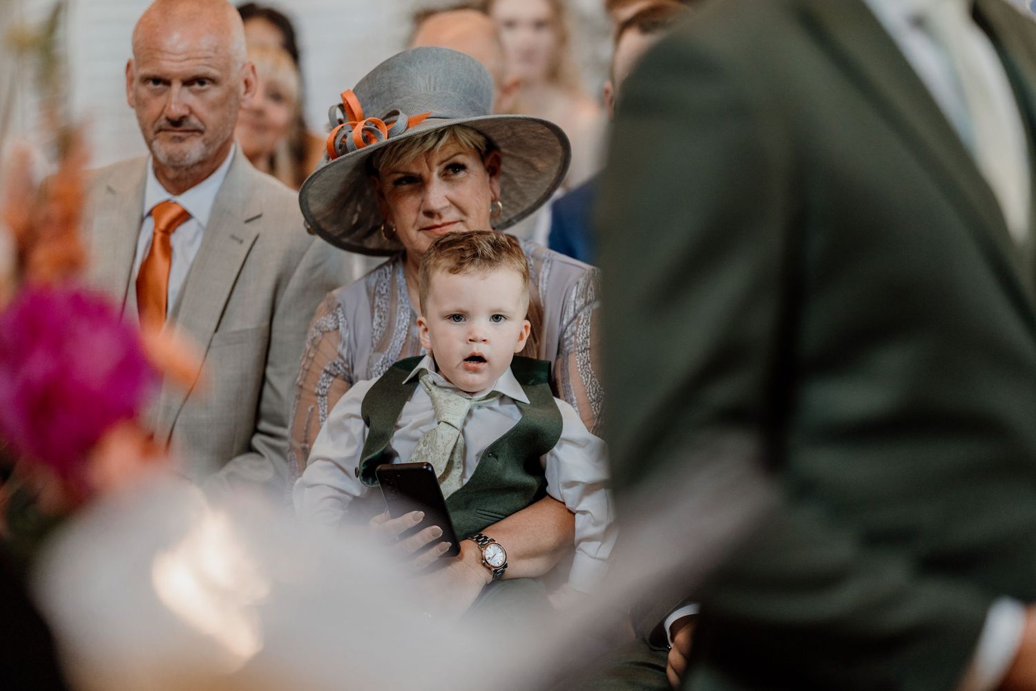 Wedding guests looking on with emotional expressions at a ceremony with natural light streaming in.